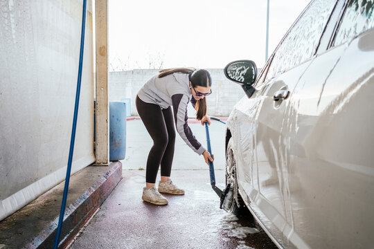 Teenager washing a car with brush at self service bay