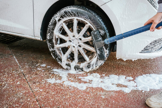 Close-up of car wheel being scrubbed with soap at wash