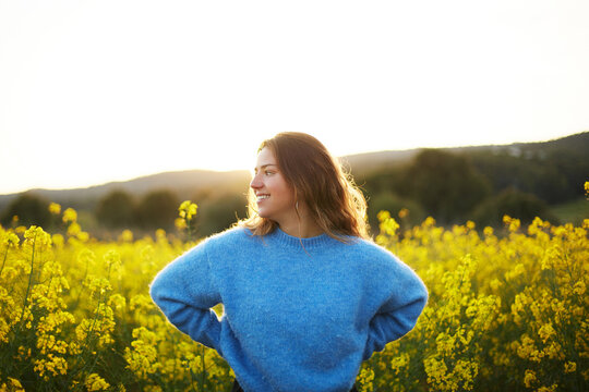 Woman enjoying spring in a field of yellow flowers