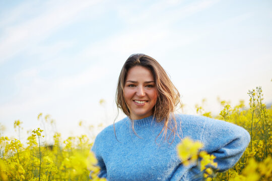 Woman enjoying spring in a field of yellow flowers
