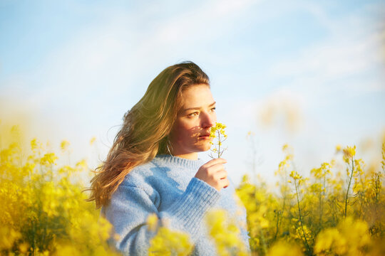 Woman enjoying scent of flowers in spring field