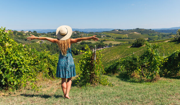 Woman with open arms in a green vineyard in Tuscany, concept of freedom