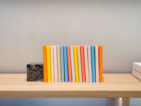 Colorful notebooks aligned with marble bookend on shelf