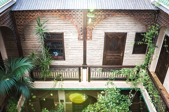 Moroccan riad courtyard with carved wood and lush greenery
