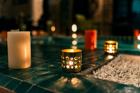 Moroccan candle holder glowing beside pool at night