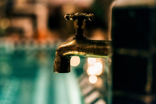 Golden poolside water tap detail with soft bokeh lights
