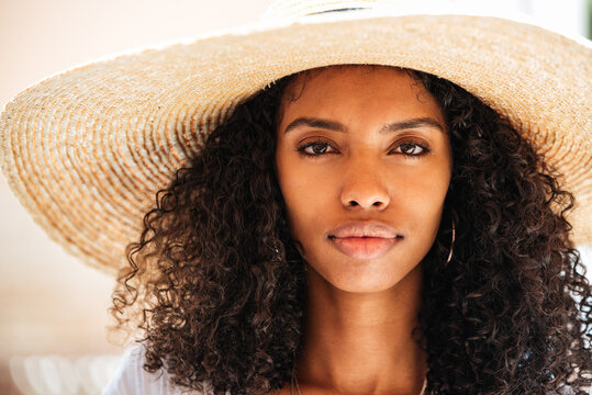 Portrait of woman in straw hat with curly hair indoors