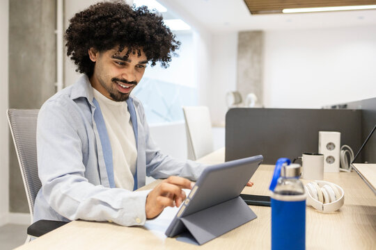 Latin man using tablet at modern office workspace desk