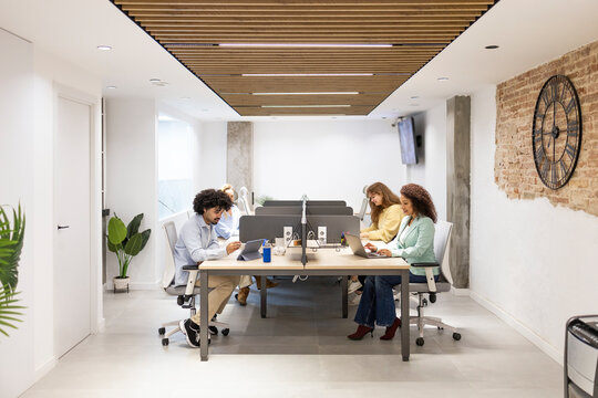 Coworking team working at shared desk in modern office
