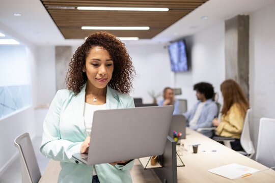 Professional woman using laptop in coworking office team