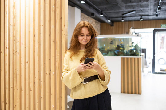 Woman using smartphone in modern office reception area