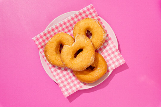 Four donuts on A checkered napkin on pink background