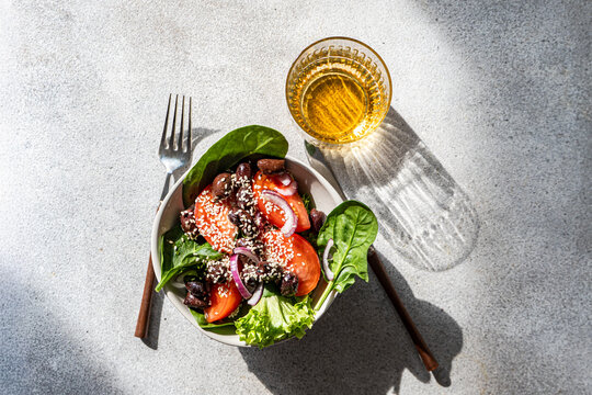 Fresh spinach salad with sesame, tomato, olive and cider