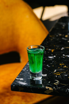 Green absinthe shot with anise and lemon on marble bar