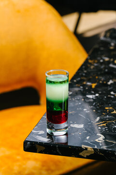 Colorful layered absinthe shot cocktail on marble bar