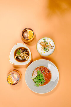Assorted soup trio with drinks on pastel background