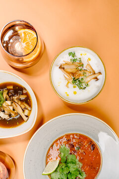 Assorted soup trio with drinks on pastel background