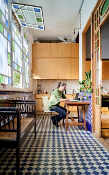 Man of Hispanic descent works from home in a bright kitchen space