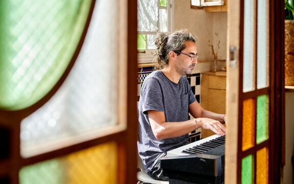 Man plays keyboard in home office in natural light during the day