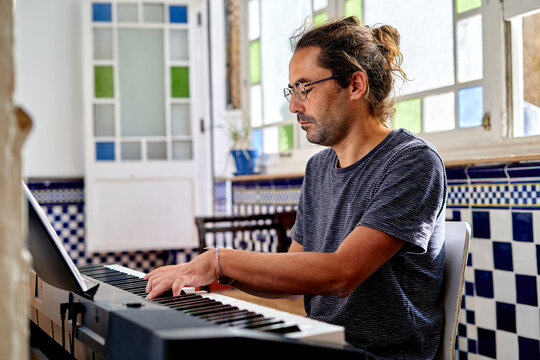 Musician plays piano in home office space during work from home hours