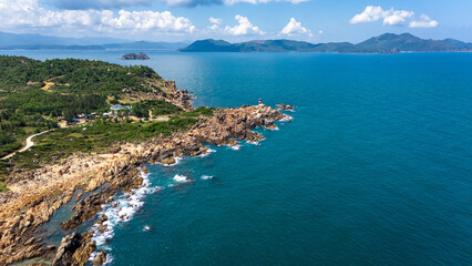 Obraz premium Breathtaking Wide Aerial Drone View of Ganh Den Lighthouse on Red Rock Coastline with Island Archipelago, Phu Yen Province, Central Vietnam, Southeast Asia