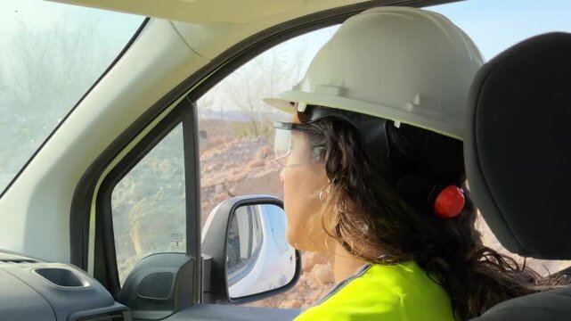 Female construction worker driving a van on a building site