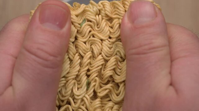 Close up of male hands breaking dry instant noodle block