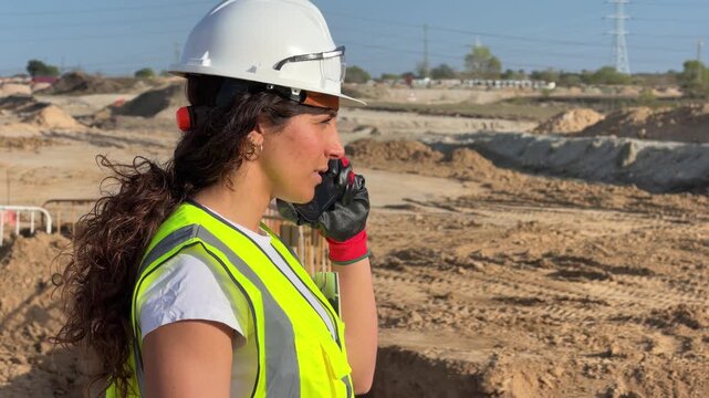 Female construction engineer talking on a walkie-talkie at a building site
