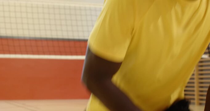 Four male athletes in yellow shirts starting warmup marching jogging lunging at net in gym