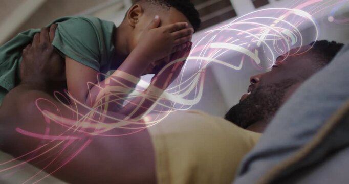Parenting father holding son on bed, ribbon sweeping and clearing as child playing peekaboo for fun