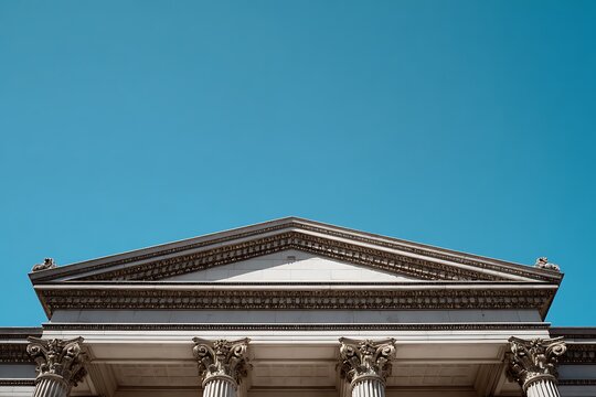 A symmetrical background of a neoclassical building's columns and pediment against a stark blue sky 