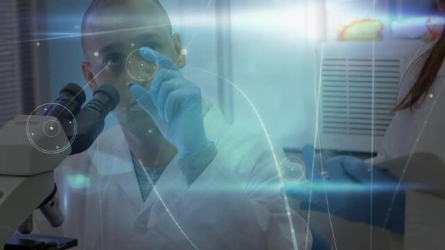Scientist adjusting microscope while colleague showing sample, graphics tracking point for research