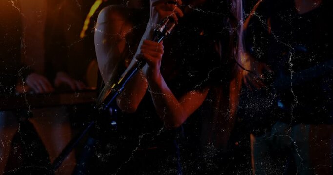 Cam panning up revealing lead singer moving to mic, gripping, singing, music,grain-overlay,orange