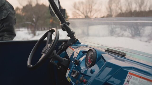 ATV steering overview. Rider prepares gear near frosty lake. Close view of ATV controls and frozen landscape. Detailed shot of rider preparing ATV with frostcovered windshield near frozen lake at dawn