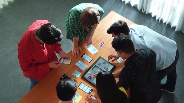 Top view of diverse business people discussing idea and designing system while using tablet with Ux, Ui design display on screen. Multicultural working together and planning strategy. Convocation.