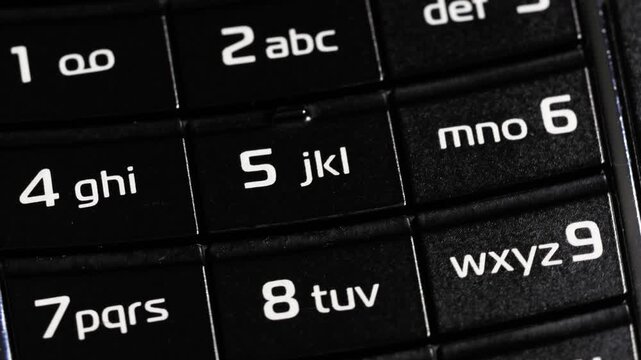 Rotating close up of black flip phone keypad with number and letter buttons
