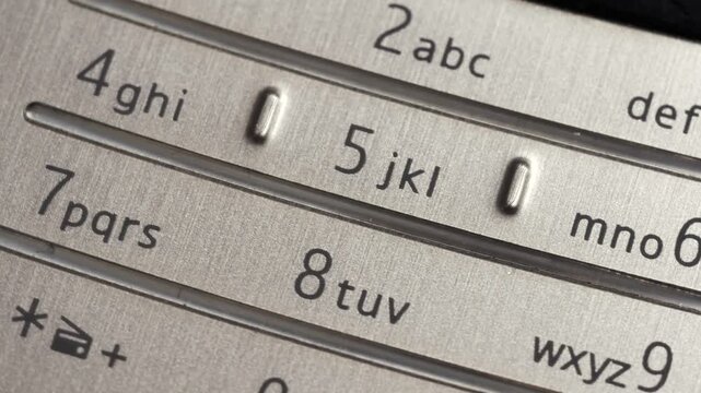 Rotating close up of silver mobile phone keypad with number and letter markings