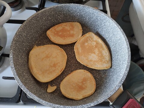 Pancakes frying in skillet on gas stove