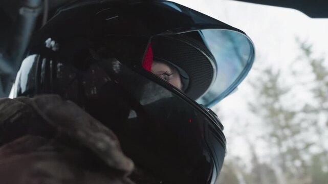 Helmeted rider eyes glance through visor forest backdrop safety gear focused gaze winter light preride anticipation visor reflection detail emphasize intensity and readiness for extreme offroad ride