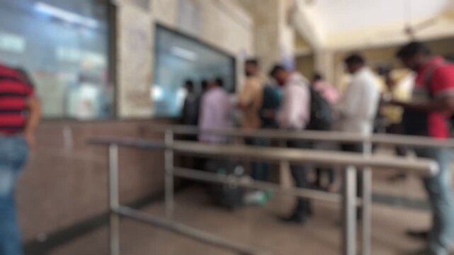 Bokeh view of passengers standing in a queue for tickets at Andheri railway station, Mumbai, India. Blurred background footage.