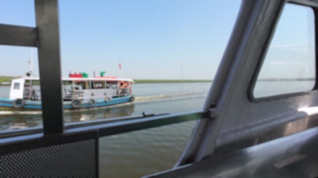 Bokeh view of a passenger ferry boat sailing on the Manori Creek river, Mumbai, India. Blurred background footage.