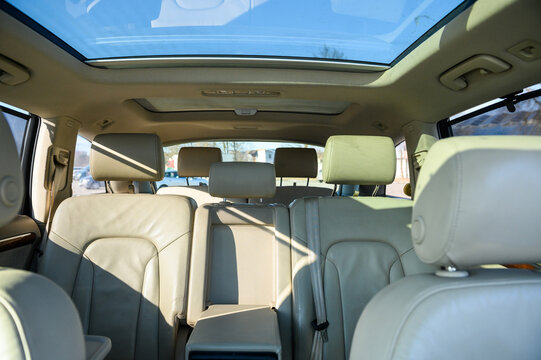 Seven-seater new car interior. Seven white back seats. New car inside. Car cleaning theme. Luxury car rear leather seats row. Interior of modern, clean expensive car. Passenger seats with leather.