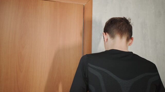 Teen pauses silently. Young person halts with eyes closed silently. Youthful individual pauses at entrance with quiet stillness. Young boy stands in silence with eyes shut before entering room