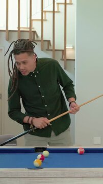 Vertical video: Shifting, man in dark green shirt chalking cue at home pool table, preparing shot