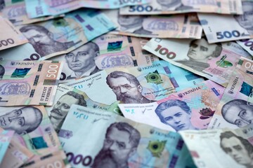 Obraz premium Ukrainian hryvnia money bills pile on table. Ukraine banknotes of UAH currency close up.