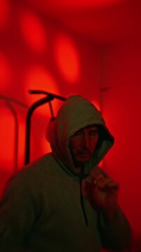 Home Glow Hoodie Workout. Neonlike Red Bokeh Illuminates Gritty Late Night Practice Mood. Practicing Streetwear Hoodie Exercises Under Glowing Red Bokeh In Late Night Surroundings. slow motion