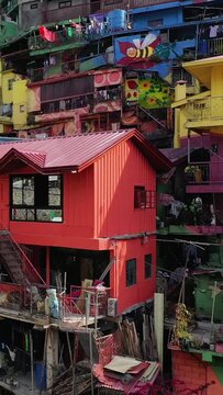 Vibrant multi-story houses painted in bright colors with murals, located on a hillside in the Valley of Colors, Baguio, Philippines.