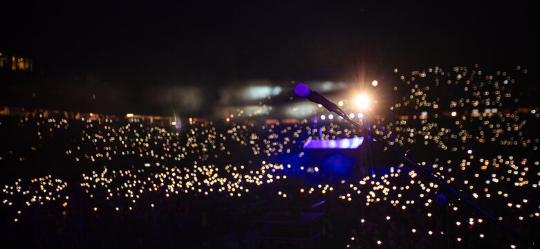 Microphone on stage against crowd with flashlights at night concert