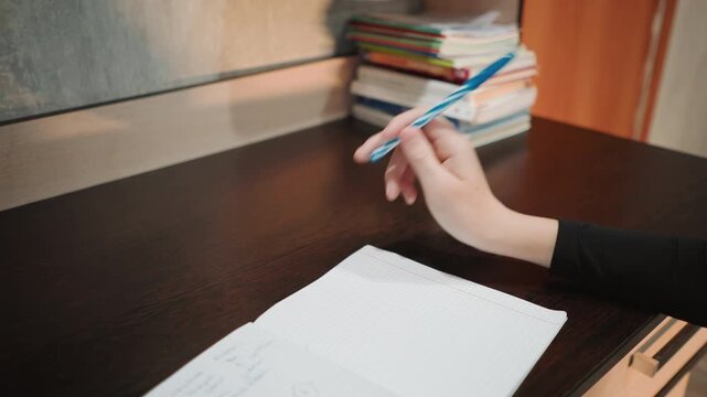 Boy scribbles calmly at his desk. Child concentrates on reading while boy writes peacefully. Young child is quietly reading while another boy scribbles thoughtfully at his workspace