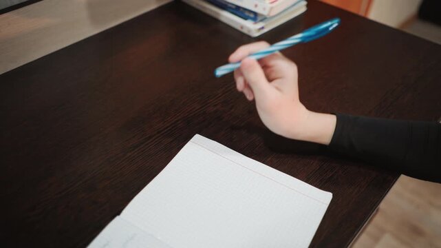 Notebook writing scene. Dark desk with handwritten notes. Person taking notes at desk with cozy indoor illumination. Handwriting in notebook on dark desk with books and calm environment